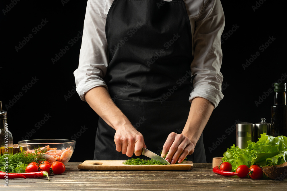 Professional chef cuts greens for salad with shrimps, the concept of seafood and healthy food. Horizontal photo, menu, recipe book