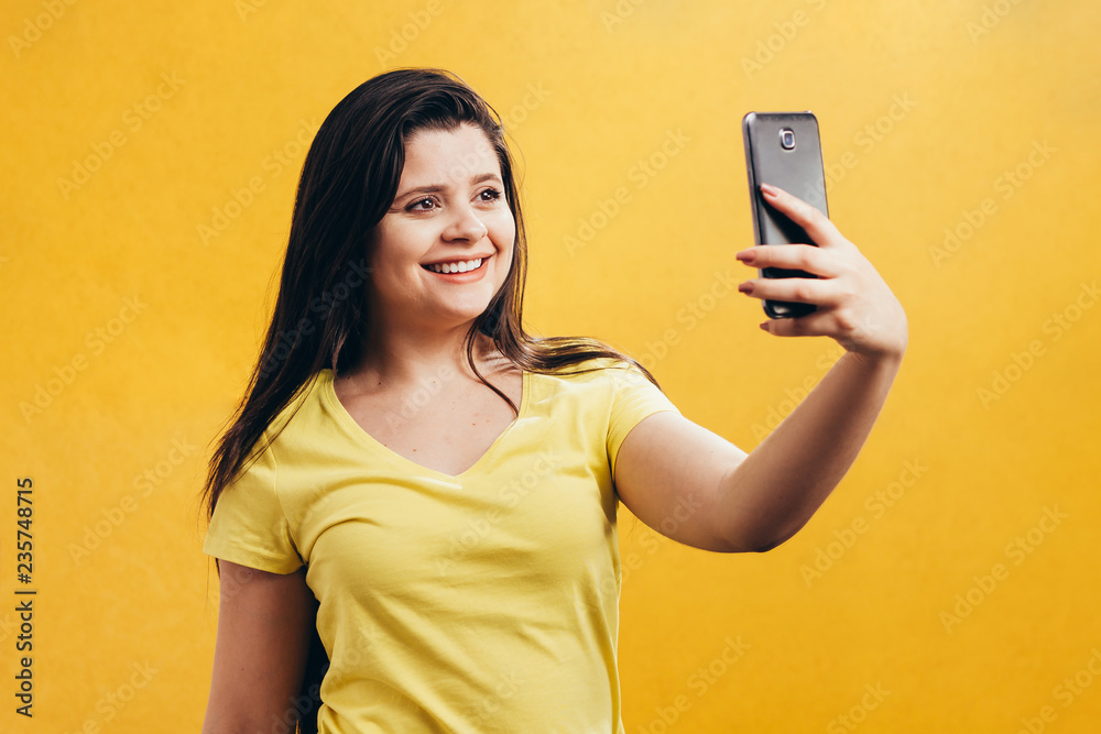 Woman on phone isolated. Portrait of young girl using smartphone over yellow background Woman on phone isolated. Portrait of young girl using smartphone over yellow background