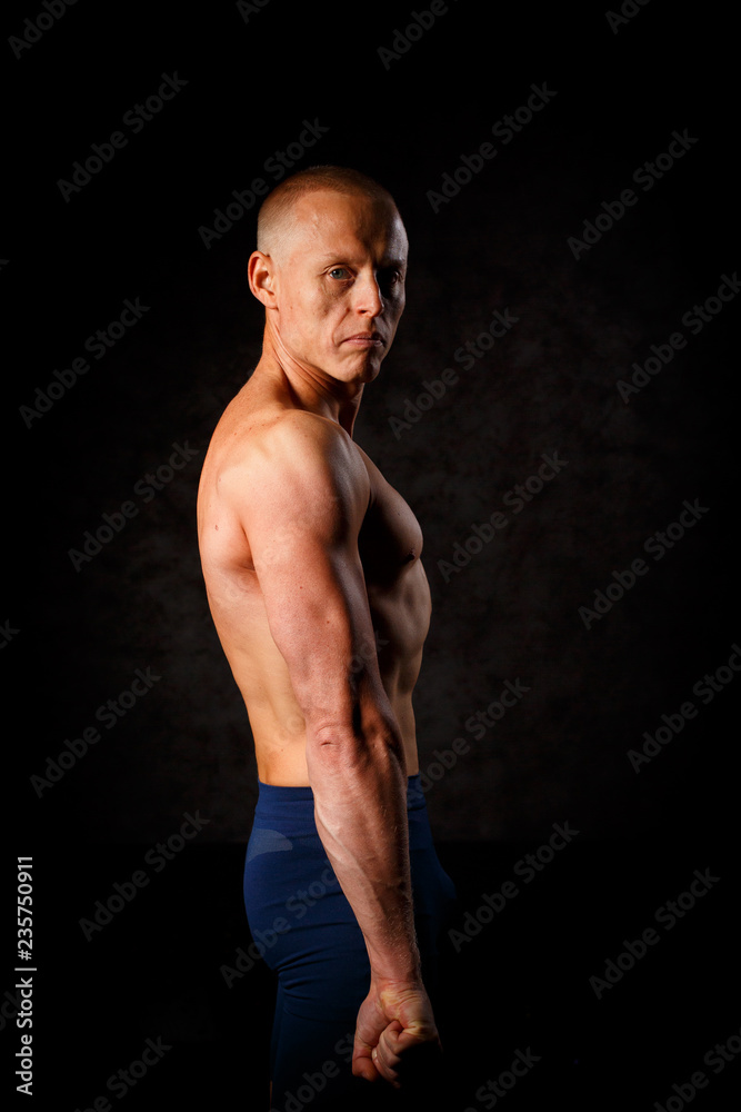 Fototapeta premium A muscular tattooed man on a dark background.