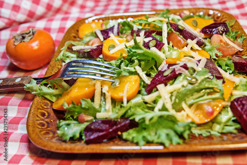 Healthy salad with lettuce salad, persimmon and beets. Persimmon salad. Diet. Vegetarian food.