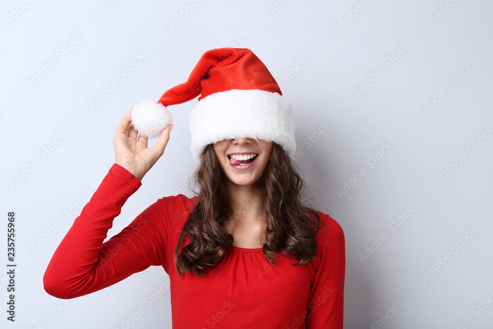 Beautiful girl in santa hat on grey background Beautiful girl in santa hat on grey background