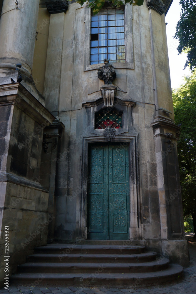An ancient stone baroque cathedral with a copper dome and stucco molding. Facade of Dominican Cathedral in Lviv City, Ukraine