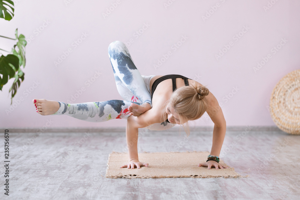 Yoga woman training on exercise mat and doing balance yoga poses.  Astavakrasana or asymmetrical arm balance pose. Wellness and healthy  lifestyle Stock Photo