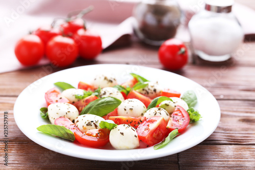Mozzarella, tomatoes and basil leafs on brown wooden table