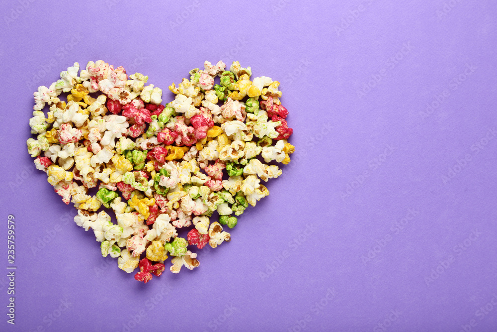 Colorful popcorn in heart shape on purple background