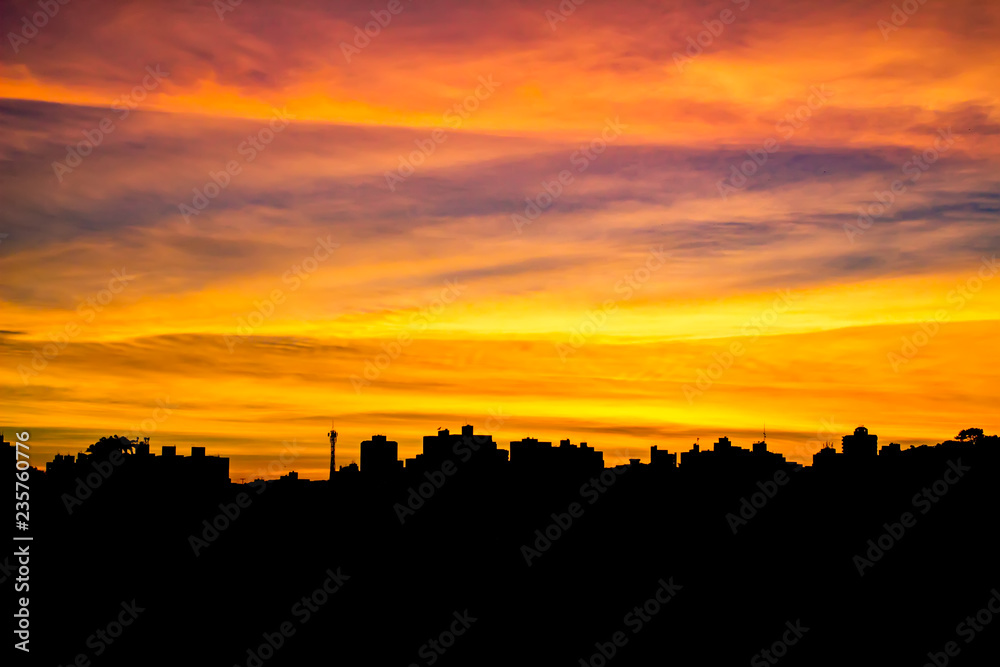 Silhouette of city building at sunrise with yellow clouds and blue sky