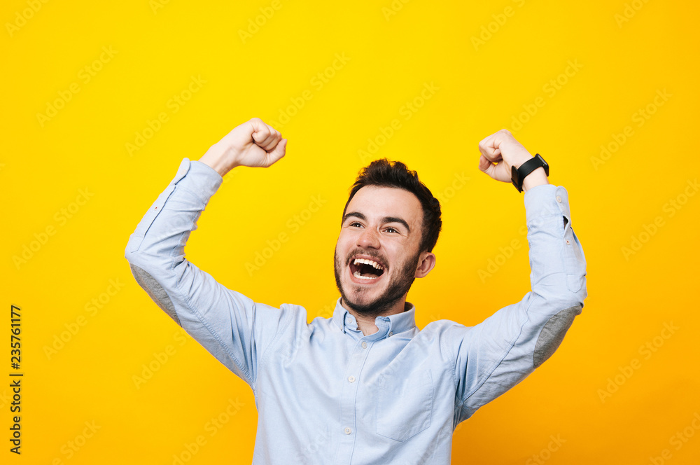 Fototapeta premium Portrait of a satisfied young man celebrating success isolated over yellow background