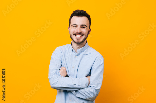 Portrait of handsome young guy standing against yellow wall.