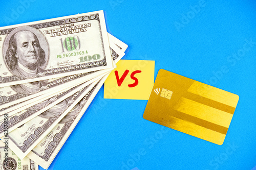 Choice among hundred dollar bills and Credit card on blue background. Concept of cash vs bank transfers.