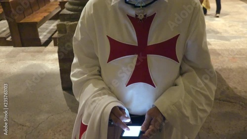 Catholic Templar Knight using smart phone after Holy Mass