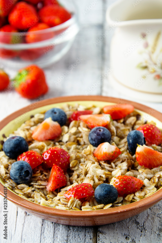 Healthy Homemade Oatmeal with Berries - fresh strwberries and blueberries, for Breakfast. Rustic white wooden table.