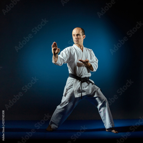 Athlete trains formal karate exercises on a blue tatam