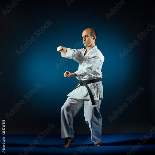 On the blue tatami athlete trains formal karate exercises