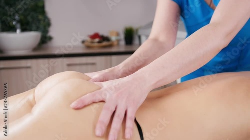 A professional masseur massaging beautful client s back in a light. Relaxing massage photo