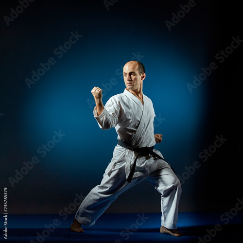 On the blue tatami sportsman performs formal karate exercises