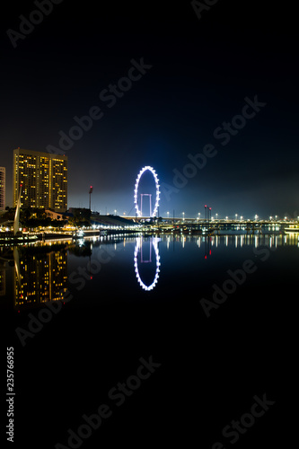 A night time image of the Singapore Flyer reflecting in the waters of Marina Bay. photo