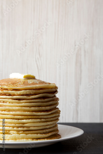 Homemade pancakes with butter on white plate, side view. Close-up.