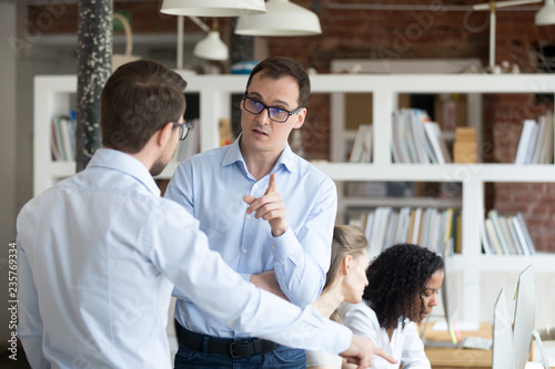 Middle aged angry mentor, coach blaming furious subordinates, boss criticize work of man intern, trainee in office, worker justifying, discussing with supervisor, businesspeople arguing photo