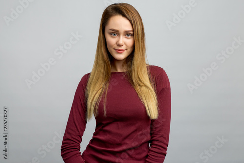 Isolated shot of a nice brunette. The girl has an attractive appearance, healthy skin, dressed in a casual sweatshirt, posing on a white background in the Studio