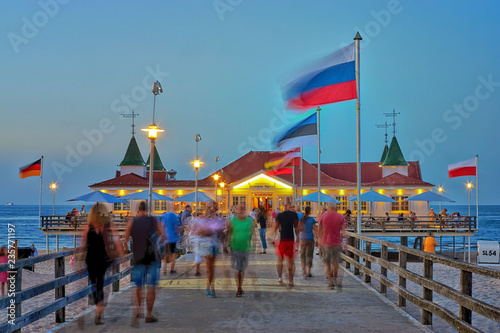 Fototapeta Naklejka Na Ścianę i Meble -  Pier Ahlbeck on the Baltic Sea with national flags in the wind. - Letters with Historische Seebrücke Ahlbeck means Ahlbeck Historic Pier.