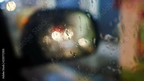 blurred defocus bokeh footage zoom in after finish raining water on side car mirror reflection window of car parking on street  with light in the dark night,