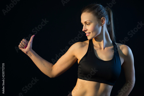 beautiful young athletic girl with an excellent figure on a black background with a gesture of hand © Alexandr
