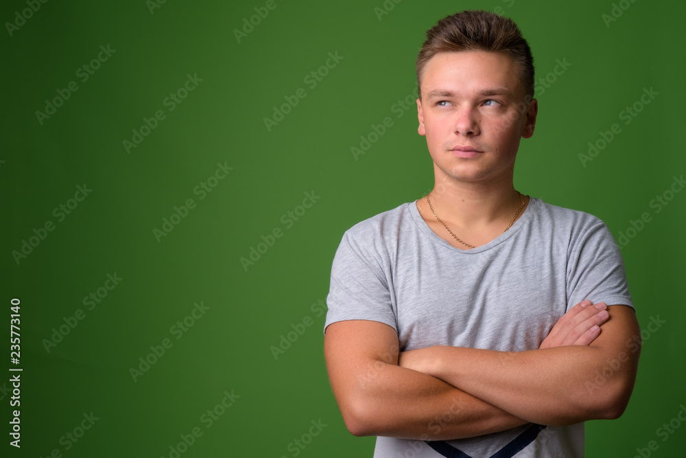 Studio shot of young handsome man against green background