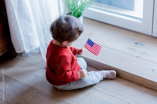 Little baby boy with USA flagg sitting on a floor at home photo