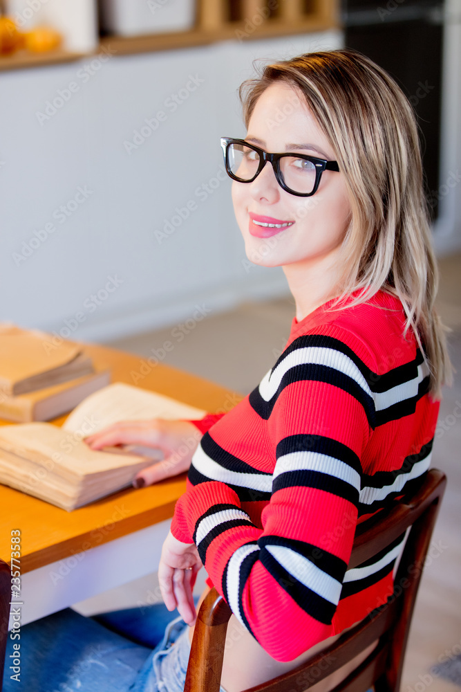 Adult caucasian girl in red sweater with books sitting at table with Christmas decoration at home. Adult caucasian girl in red sweater with books sitting at table with Christmas decoration at home.