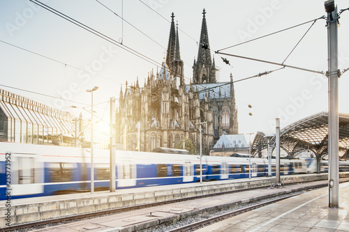 Schneller Zug fährt mit Kölner Dom im Hintergrund bei Sonnenuntergang
