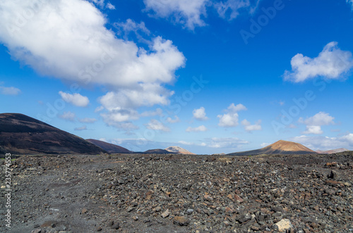 Blick über ein Lavafeld auf Lanzarote mit Vulkanen im Hintergrund
