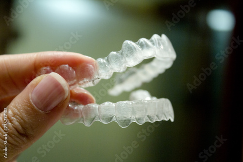 Womans hand holding transparent dental orthodontics to correct the dental alignment