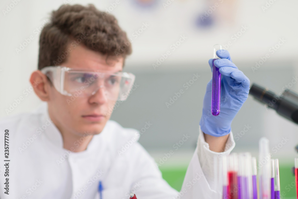 Young male Laboratory scientist working at lab with test tubes and microscope, test or research in clinical laboratory.Science, chemistry, biology, medicine and people concept. Young male Laboratory scientist working at lab with test tubes and microscope, test or research in clinical laboratory.Science, chemistry, biology, medicine and people concept.
