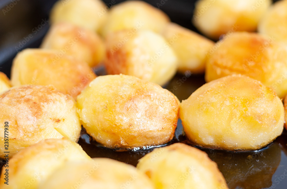 Crispy roast potatoes sizzling away in a baking tray