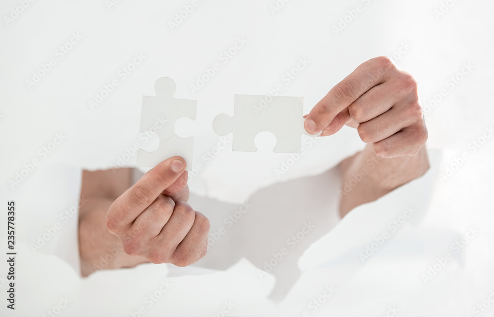 man connecting pieces of puzzles, breaking the wall of paper. man connecting pieces of puzzles, breaking the wall of paper.
