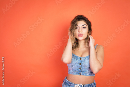 portrait of beautiful girl with curly hair in jeans clothes on red background