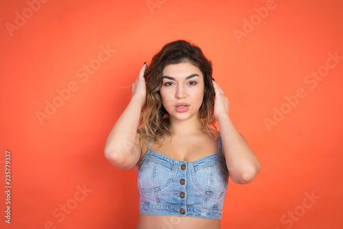 portrait of beautiful girl with curly hair in jeans clothes on red background