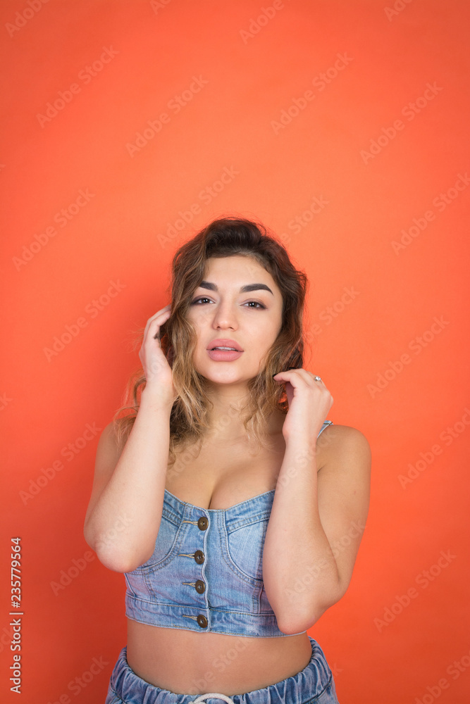 portrait of beautiful girl with curly hair in jeans clothes on red background portrait of beautiful girl with curly hair in jeans clothes on red background