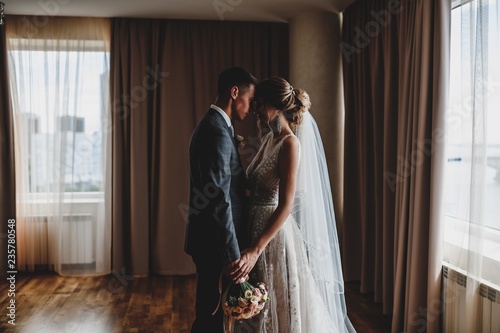 Wedding photo shoot of the newlyweds in a dark hotel room.