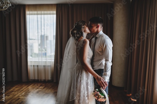 Wedding photo shoot of the newlyweds in a dark hotel room.
