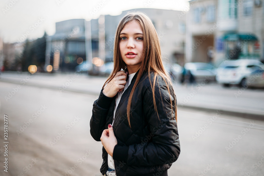fashion Girl wearing t-shirt and leather jacket posing against street , urban clothing style.