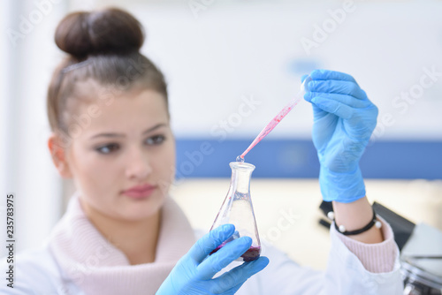 Young female Laboratory scientist working at lab with test tubes and microscope, test or research in clinical laboratory.Science, chemistry, biology, medicine and people concept.