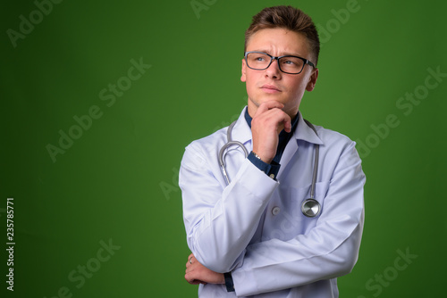 Young handsome man doctor against green background