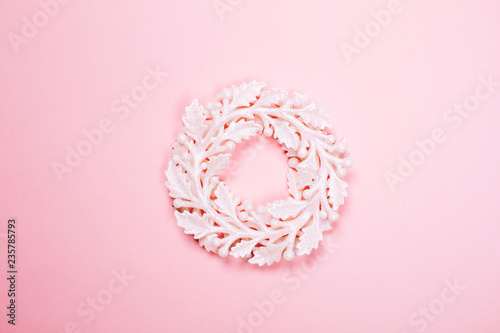 Christmas decorative white wreath on pink pastel background. Macro. Festive concept.