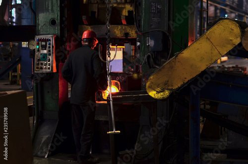 Hot iron in smeltery held by a worker. High precision hot forging product, automotive part production by hot forging process, automatice line hot forging. iron melting recycling work.