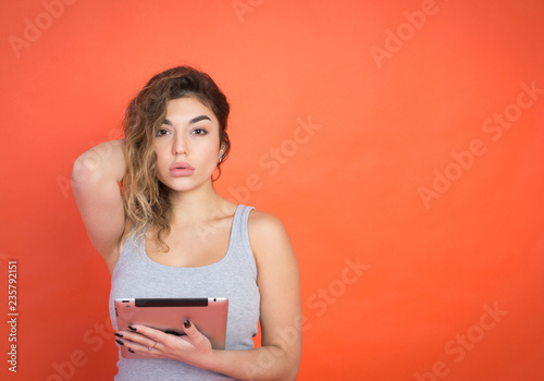 Portrait of a laughing woman using tablet computer isolated on a red background and looking at camera