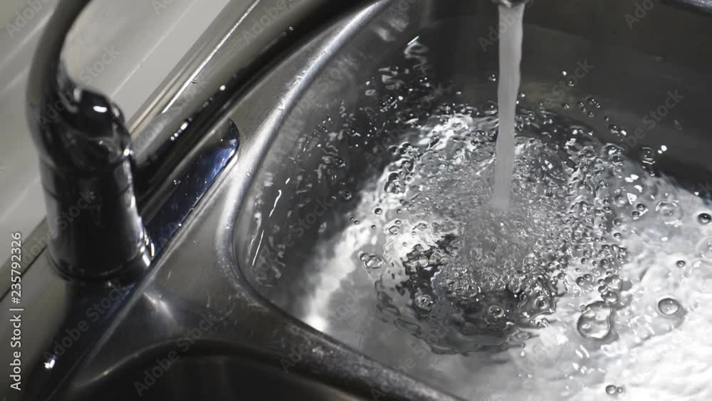 Slow motion kitchen sink filling with water. Dramatic and moody