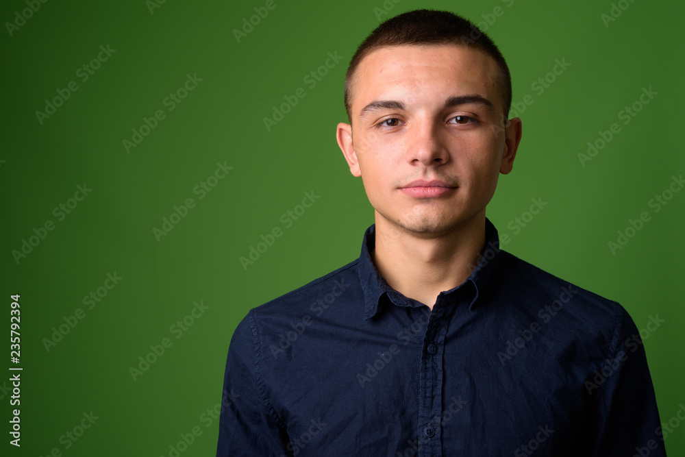 Studio shot of young handsome businessman against green backgrou Studio shot of young handsome businessman against green backgrou