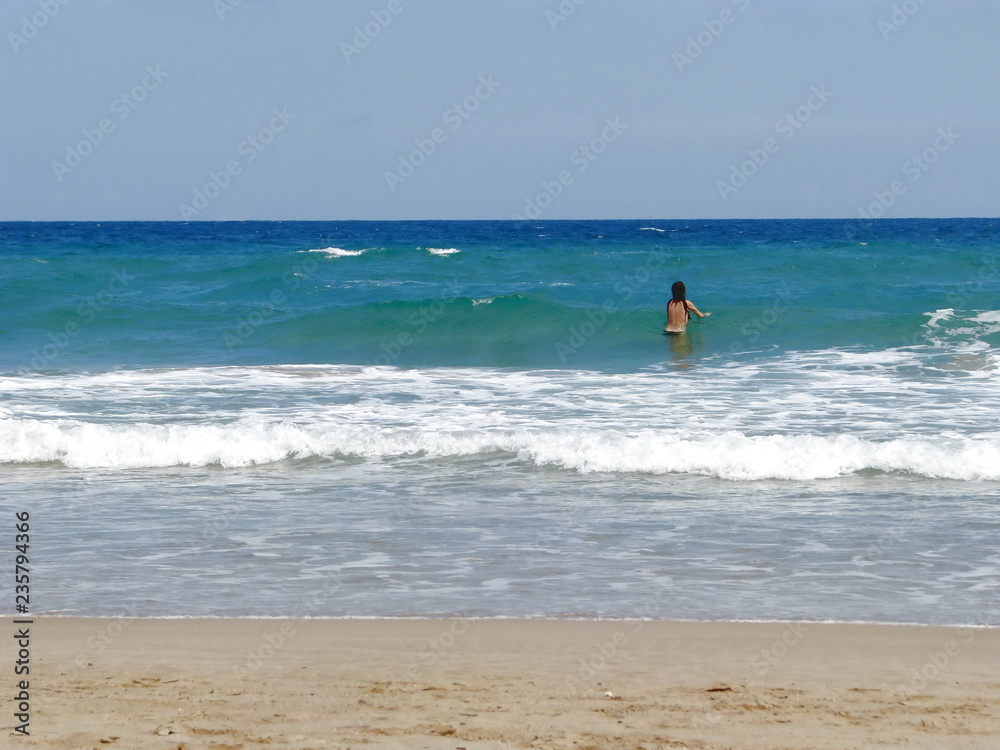 Woman bathes in the sea alone on the beach