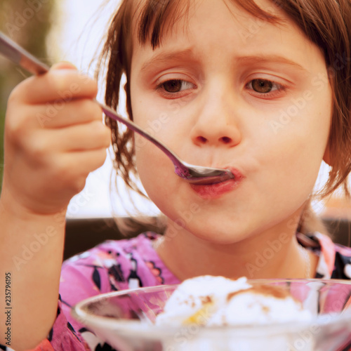 Tasty ice cream. Pretty little child girl eating ice cream outdoors. (food, dessert, childhood concept)